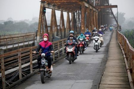 People wear protective masks to protect themselves against coronavirus while driving along Long Bien bridge in Hanoi, March 16, 2020. Reuters/Kham