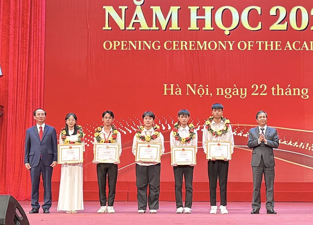 Assoc. Prof. Dr. Trieu Van Cuong, Vice Minister of Home Affairs, and Assoc. Prof. Dr. Nguyen Ba Chien, NAPA President, presenting laurels and certificates of merit to the new students who achieved the highest entrance exam scores for the 2024 full-time university program.