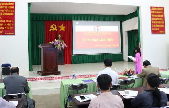 Quần chúng Trần Thị Mai Tuyên thệ trước cờ đảng, cờ tổ quốc, chân dung chủ tịch Hồ Chí Minh và sự chứng kiến của toàn thể đảng viên trong Chi bộ
