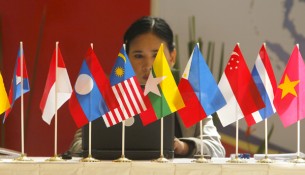 A woman sits in front of flags of the ASEAN at Bali Nusa Dua Convention Centre in Bali
